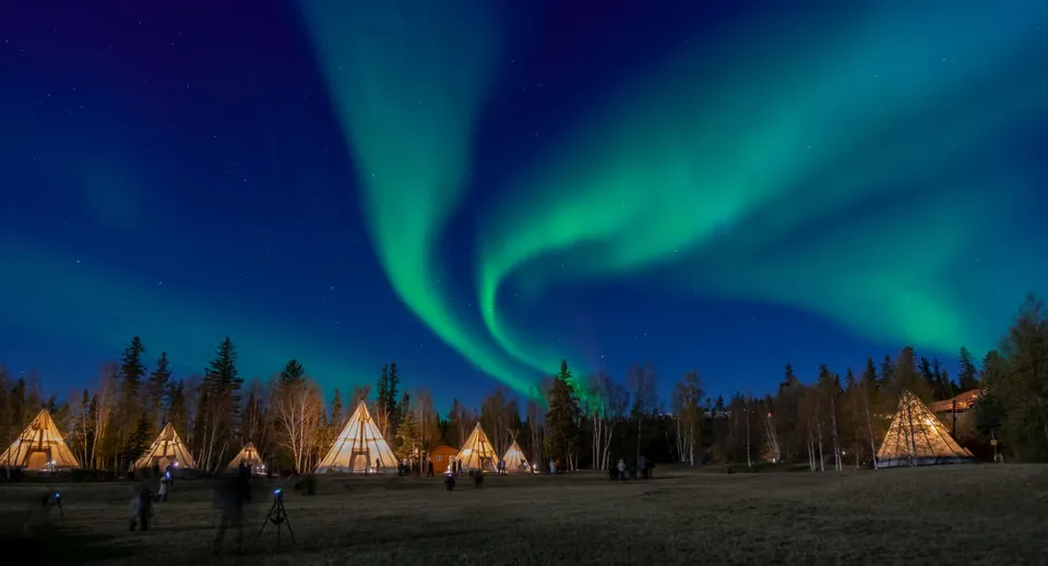 L'aurora boreale illumina il cielo notturno sopra un campo con tepee nell'area della Grant Park High School.