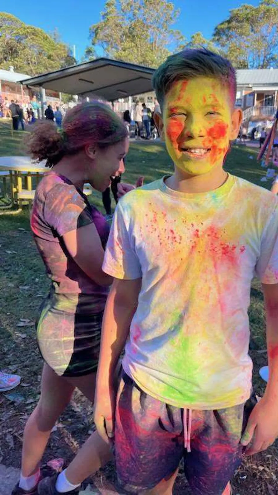 Due studenti del Georges River College con polvere colorata sul viso e sui vestiti all'aperto.