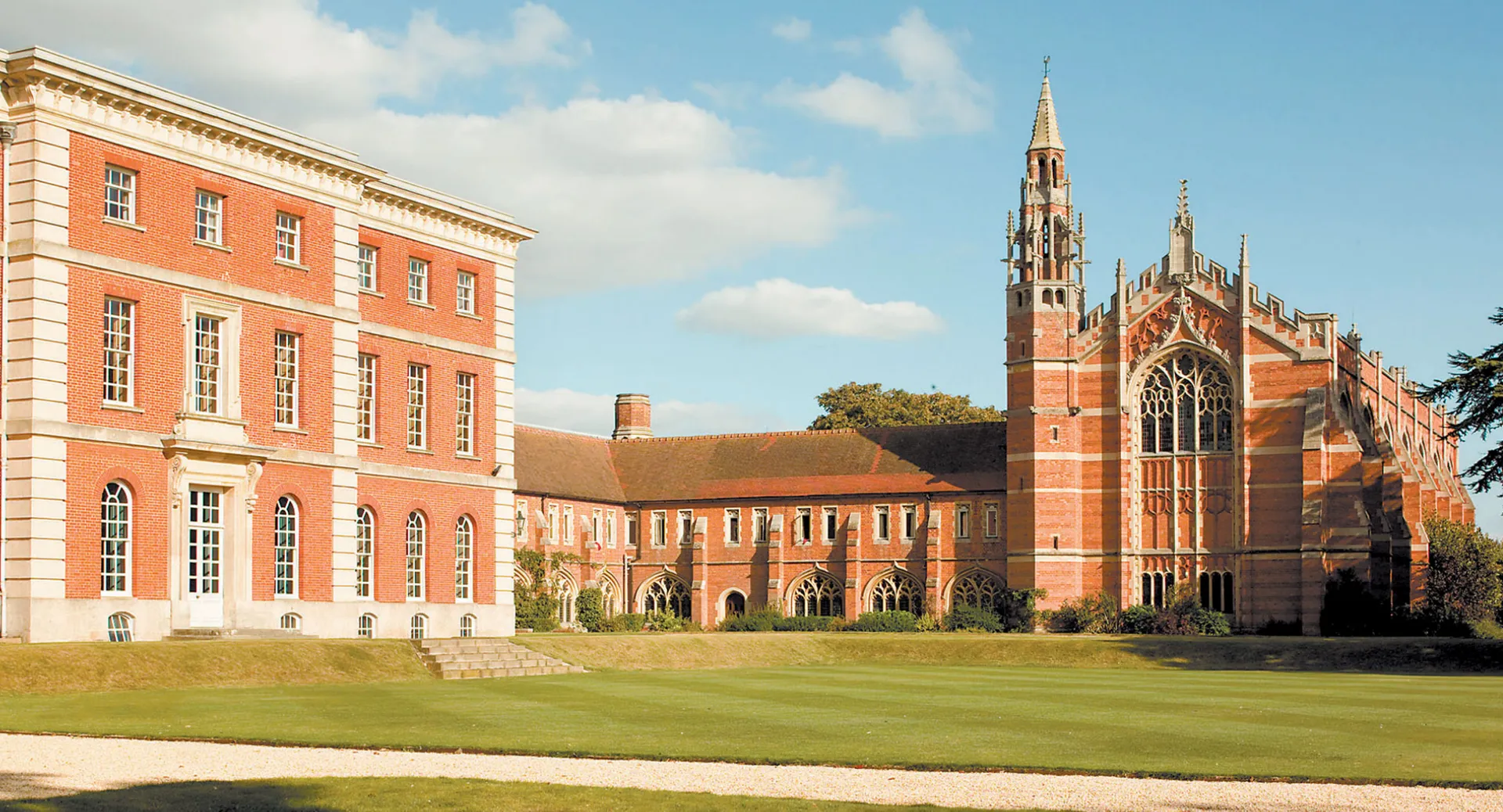 Gli edifici storici in mattoni del Radley College con una cappella e un prato ben curato in primo piano.