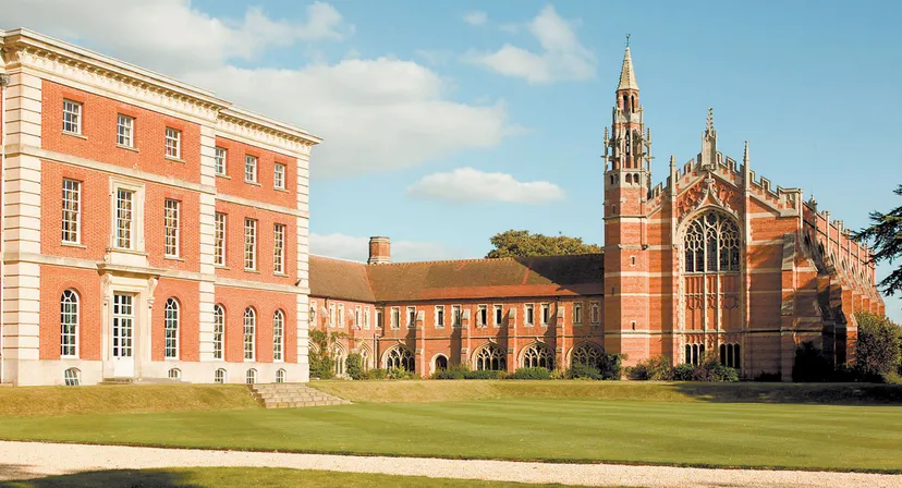 Gli edifici storici in mattoni del Radley College con una cappella e un prato ben curato in primo piano.