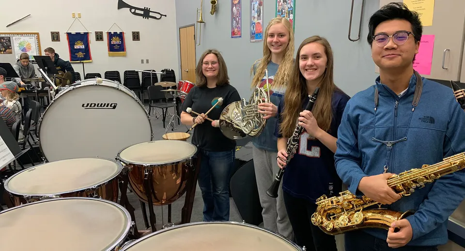 Un gruppo di studenti e studentesse con strumenti musicali nell'aula di musica della Colorado Springs Christian School.