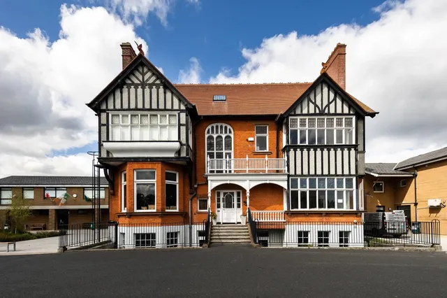 Das historische Hauptgebäude der Sandford Park School in Dublin mit roter Klinkerfassade und Fachwerkelementen.