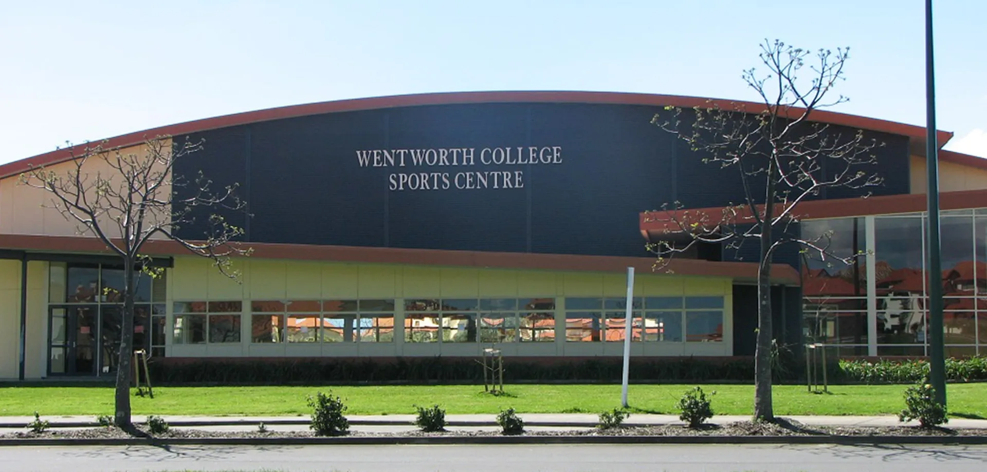 Il Wentworth College mostra il suo grande centro sportivo con tetto curvo e vegetazione circostante.