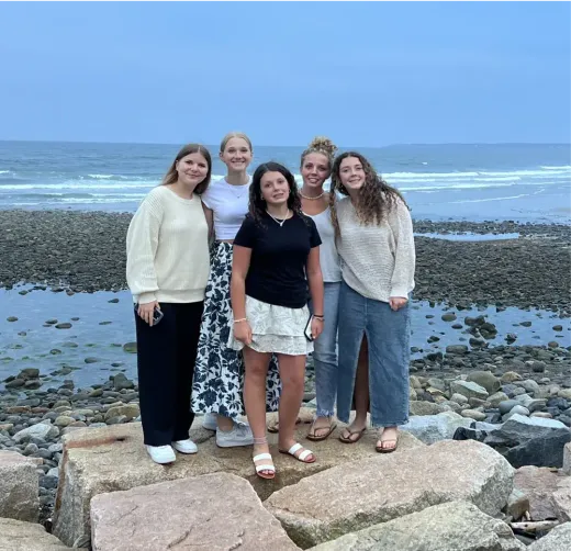 Maja e le sue amiche posano su rocce in riva al mare al tramonto negli Stati Uniti