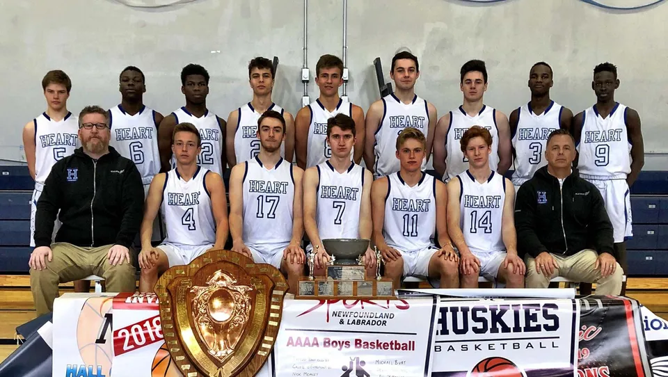 La squadra di basket della Holy Heart of Mary High School in posa con un trofeo davanti al campo da basket.