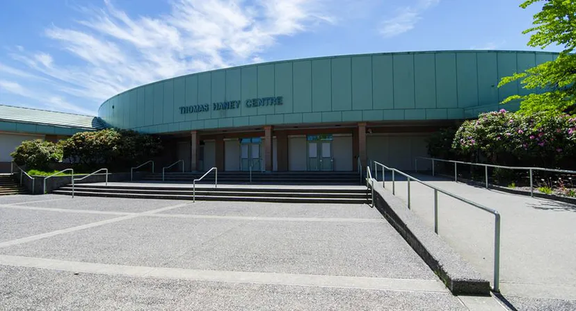 L'edificio principale verde e curvo della Thomas Haney Secondary School con l'area d'ingresso e il piazzale circostante.