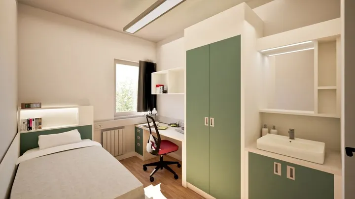 Habitación individual de la residencia con cama, escritorio, armario verde y lavabo