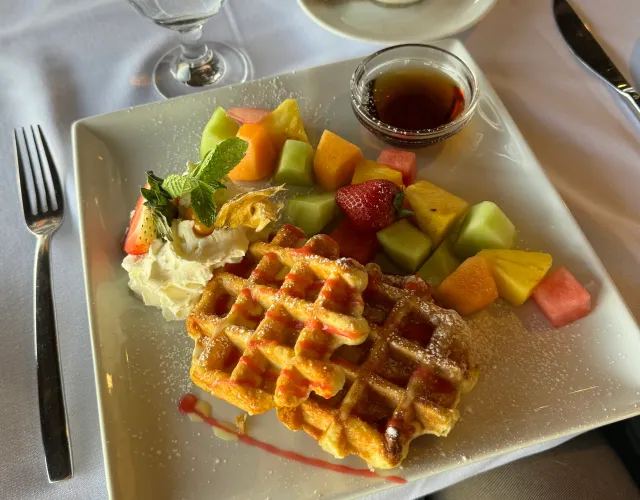 Waffle con frutta fresca, panna e sciroppo d'acero servito su un piatto