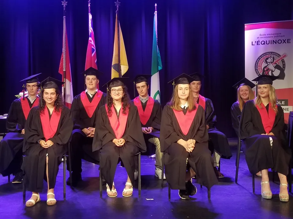 Neodiplomati e neodiplomate della École élémentaire et secondaire publique L'Équinoxe in abito accademico su un palco durante la cerimonia di diploma.