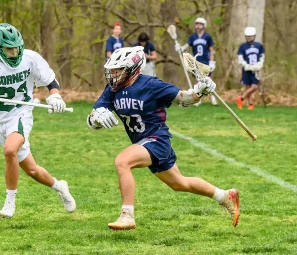 Un giocatore di lacrosse della The Harvey School corre sul campo durante una partita.