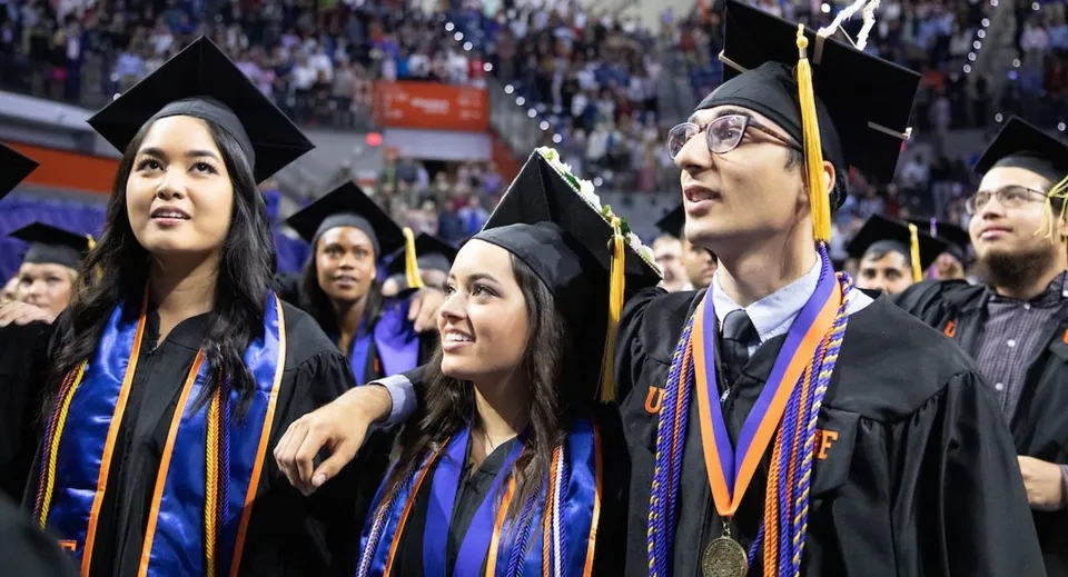 Un gruppo di diplomati della Notre Dame High School si trova insieme in abito da cerimonia festeggiando il loro diploma.