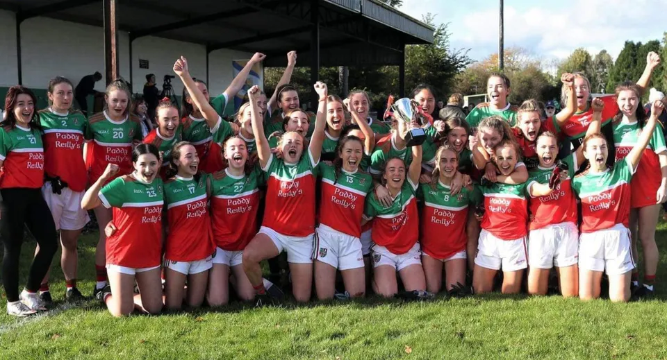 Un gruppo di giovani atlete della Ardscoil Phadraig festeggia insieme su un prato.