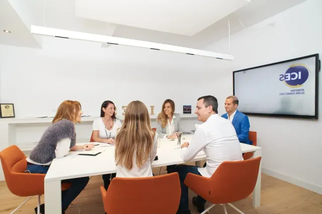 Equipo de ICES conversando alrededor de una mesa blanca en la sala de reuniones