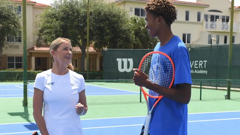Un'allenatrice e un giovane tennista parlano su un campo da tennis della Evert Tennis Academy.