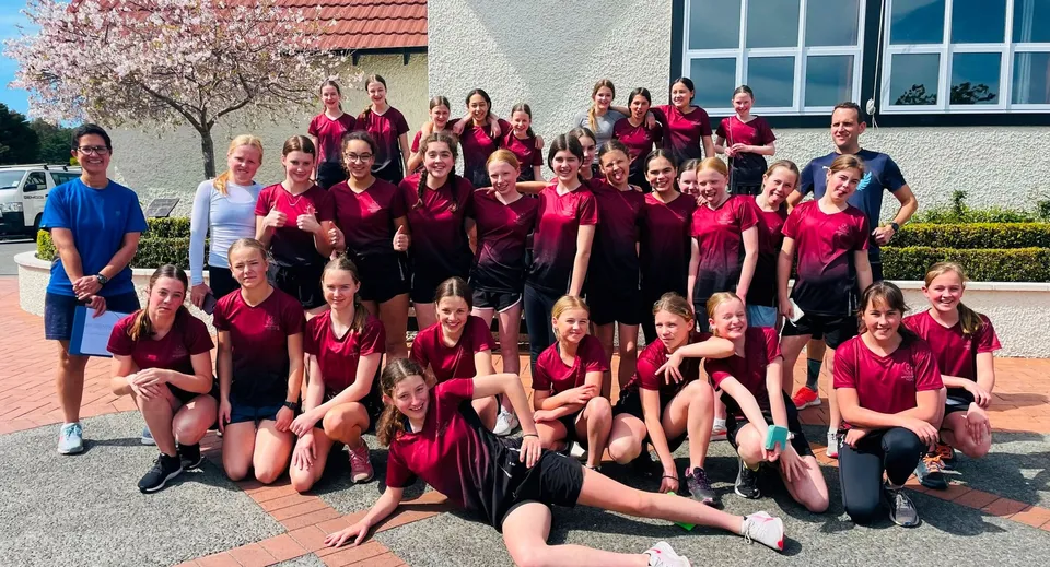 Un gruppo di studentesse in divisa rossa e nera si trova davanti all'edificio di Woodford House.