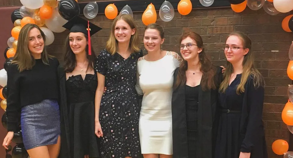 Un gruppo di studentesse in abbigliamento formale posa davanti a uno sfondo festivo nel campus del Martingrove Collegiate Institute.