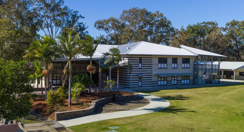 L'edificio in legno a due piani con tetto in metallo della Caloundra State High School è circondato da una rigogliosa vegetazione e palme.