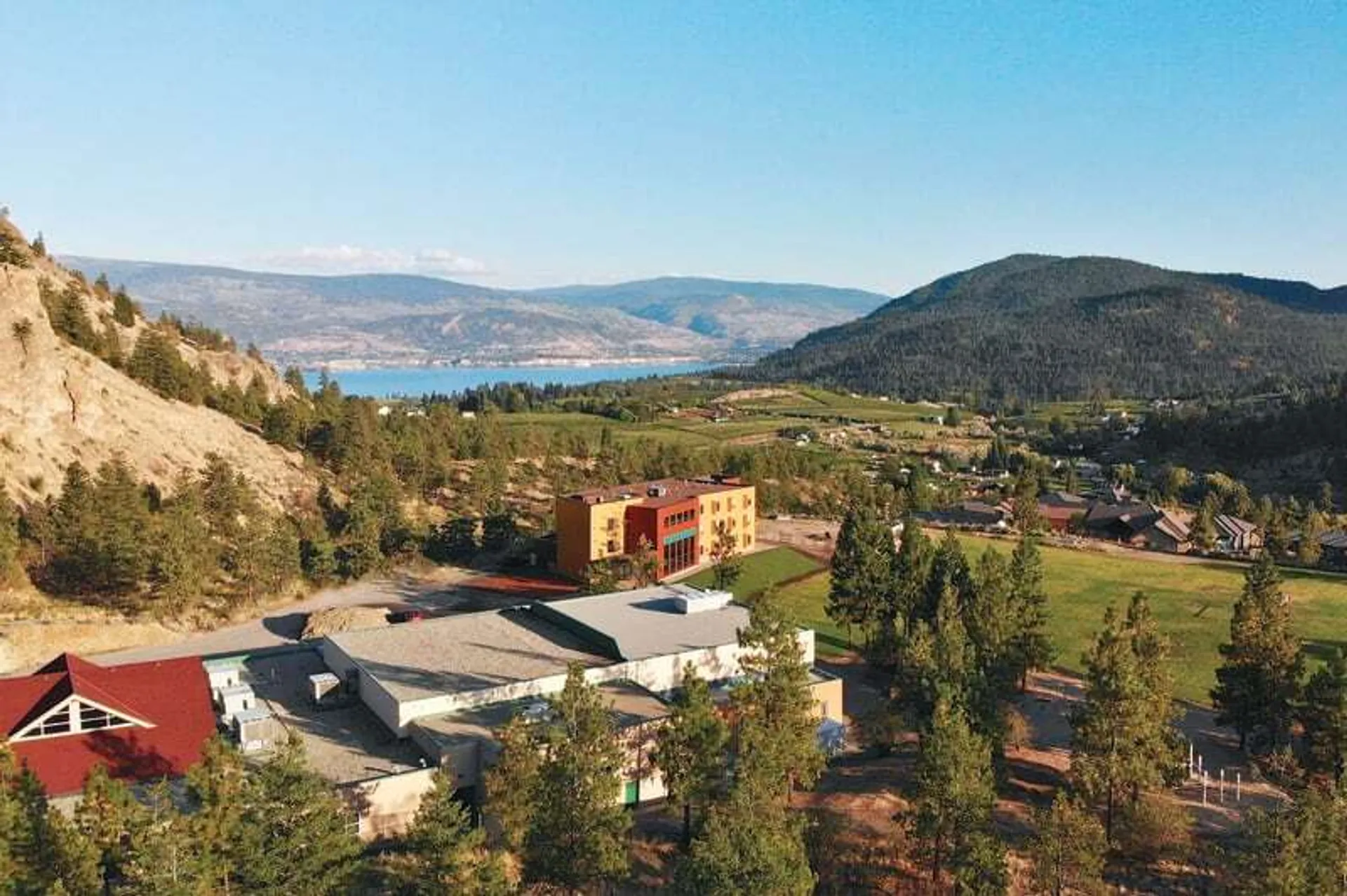 Un paesaggio pittoresco con un villaggio, colline, bosco e un lago in lontananza, senza un legame diretto con la Unisus School.