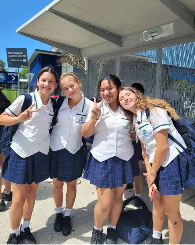 Quattro studentesse in uniforme scolastica a una fermata dell'autobus