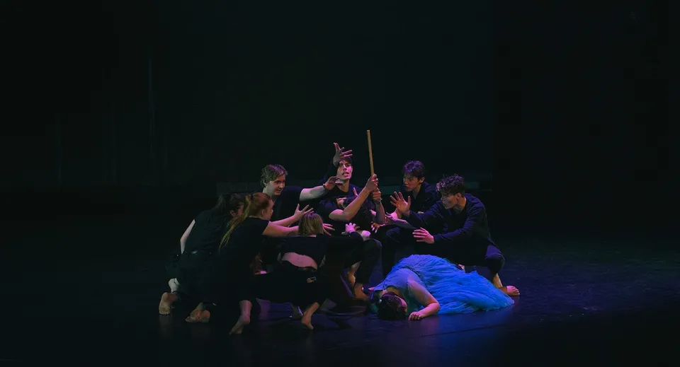 Un gruppo di studenti della Kamo High School si trova su un palco scuro, mentre una persona in abiti blu è al centro dell'attenzione.