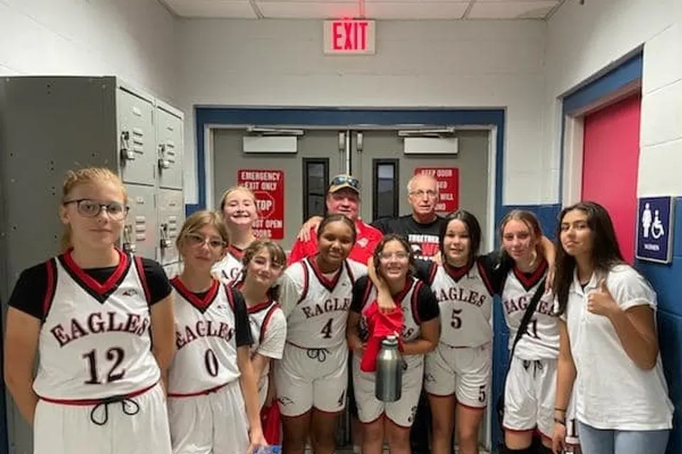 La squadra femminile di pallacanestro della Parkhurst Academy posa con due allenatori in un corridoio della scuola.