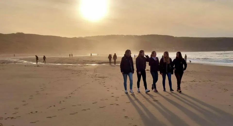 Un gruppo di studenti della Fyling Hall School cammina lungo la spiaggia al tramonto.
