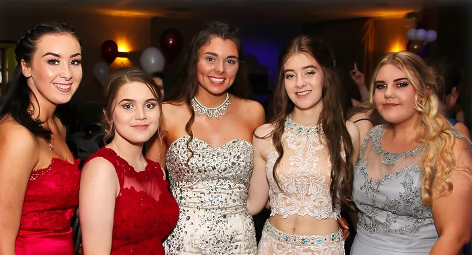 Cinque studentesse della St. Thomas More School posano in abiti formali durante una festa.