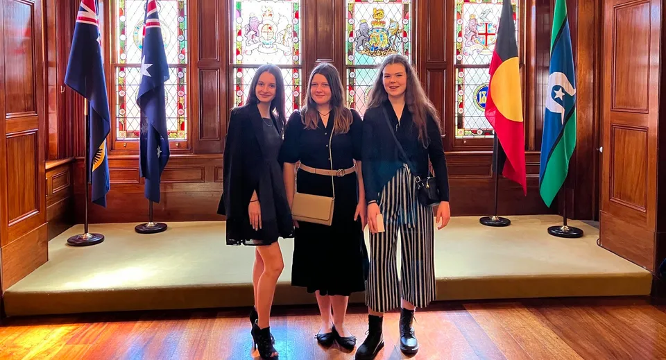 Tre studentesse in abbigliamento formale nero si trovano nella splendida hall del Springbank Secondary College.