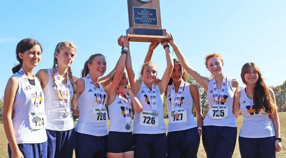 La squadra femminile della The Webb School tiene insieme una coppa sotto un cielo blu.