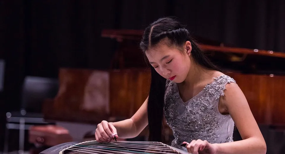 Una studentessa dell'ACG Parnell College suona concentrata uno strumento musicale sotto le luci del palco.