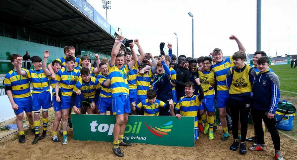 Studenti dell'Athlone Community College festeggiano insieme su un campo sportivo tenendo alta una bandiera.