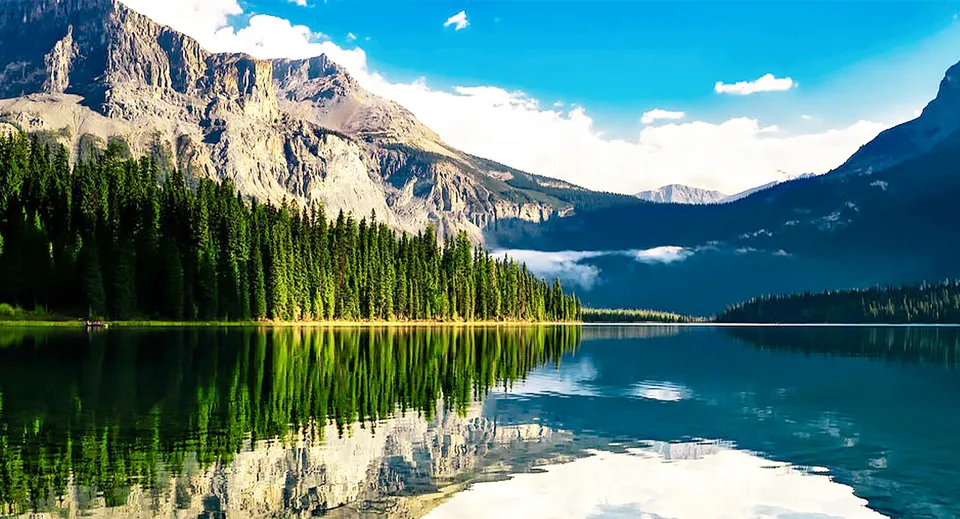 Un tranquillo lago di montagna circondato da alte montagne e fitti boschi di conifere mostra un perfetto riflesso del paesaggio.