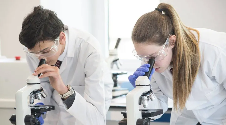 Due studenti della North London Grammar School esaminano qualcosa al microscopio in laboratorio.