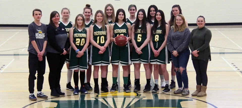 La squadra di pallacanestro femminile della Memorial Composite High School posa in maglia verde nella palestra.