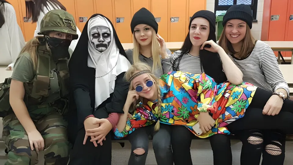Un gruppo di studentesse della École Polyvalente des Monts indossa vari costumi e posa insieme in un ambiente scolastico.