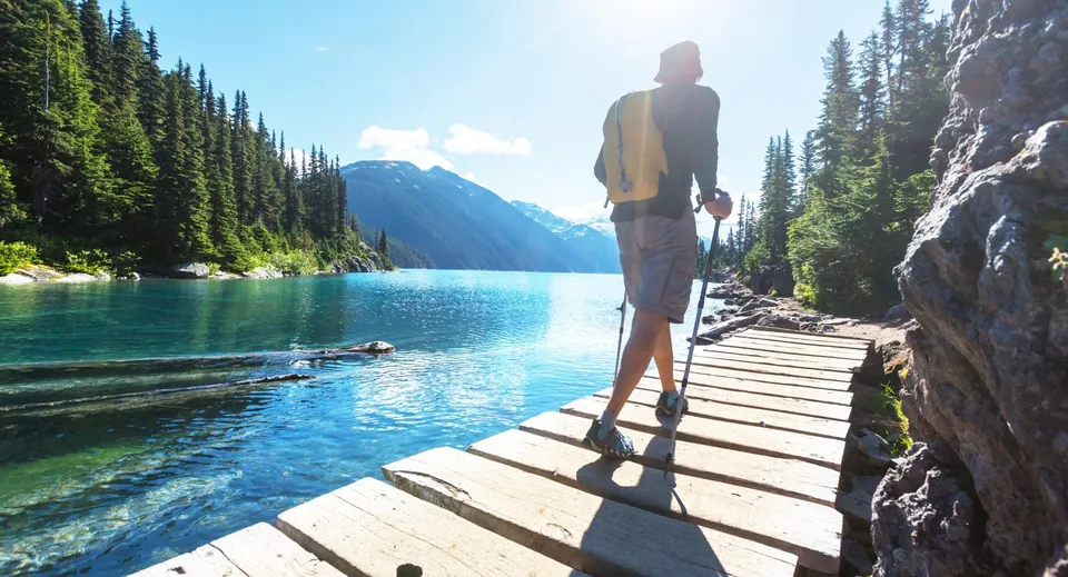 Una persona sta su un pontile e guarda un lago turchese con le montagne sullo sfondo nei pressi del Loyalist Collegiate & Vocational Institute.