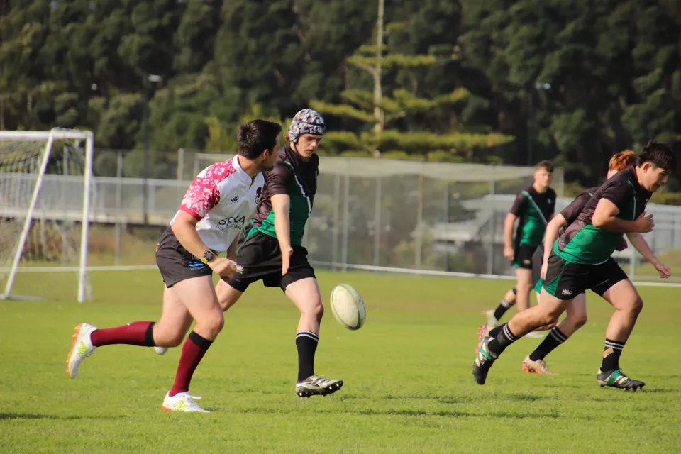 Un gruppo di studenti gioca a sport sul campo verde dell'Orewa College con una porta sullo sfondo.