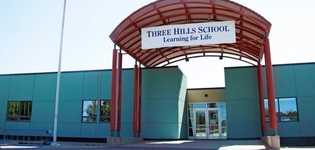 L'ingresso della Three Hills School con un tetto in tegole rosse e un cartello con il motto Learning for Life.