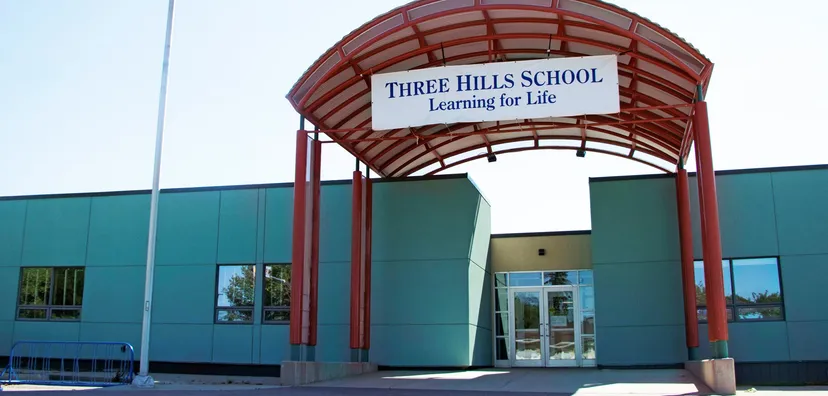 L'ingresso della Three Hills School con un tetto in tegole rosse e un cartello con il motto Learning for Life.