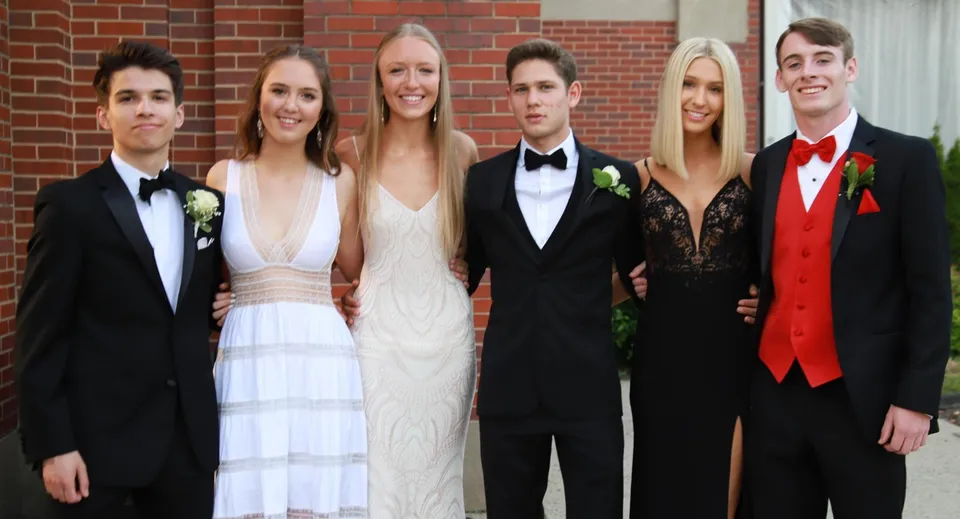 Un gruppo di sei persone ben vestite si mette in posa davanti all'edificio in mattoni della Elgin Park Secondary School.