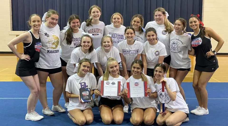 Un gruppo di giovani atlete in uniformi sportive posa nella palestra della Bishop Guilfoyle Catholic High School.