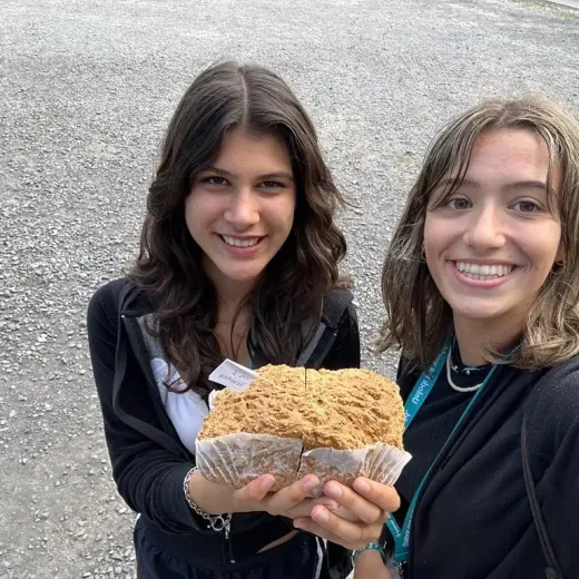 Due ragazze sorridenti mostrano dei dolci fatti in casa all'aperto
