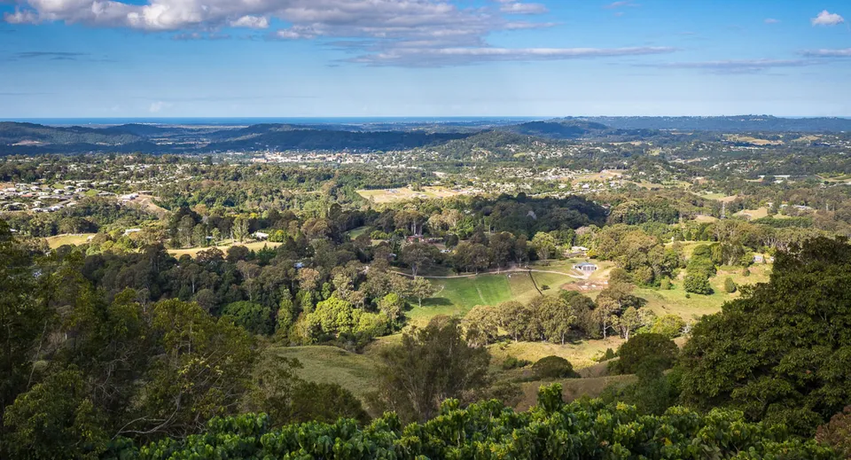 Paesaggio verde con colline, boschi e una piccola città sullo sfondo, vicino alla Burnside State High School.