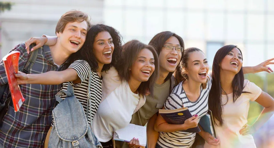 Un gruppo di studentesse del Cambridge Tutors College si abbraccia ridendo all'aperto.