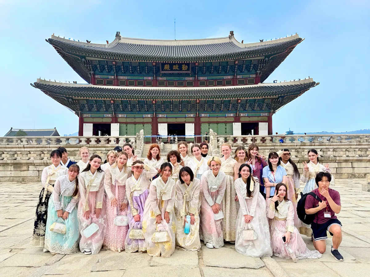 Gruppe von Studierenden in traditionellen koreanischen Hanbok vor dem Gyeongbokgung-Palast in Seoul.
