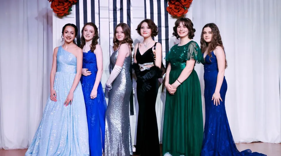 Un gruppo di sei giovani donne in eleganti abiti da sera durante un evento serale nel campus della The Webb School.