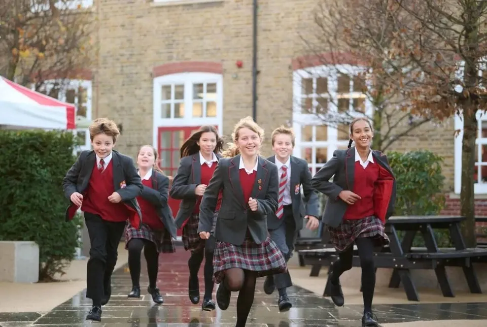 Studenti della Kingston Grammar School in divisa scolastica corrono nel cortile della scuola.