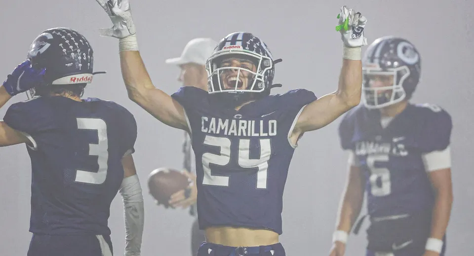 Un giocatore di football americano festeggia a braccia alzate insieme ad altri giocatori della Three Oaks Senior High.