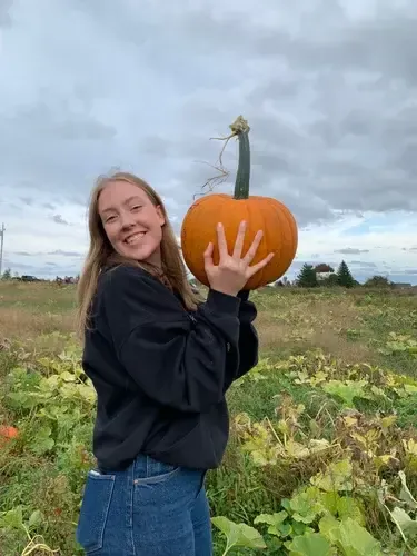 Chica sujetando una calabaza grande en un campo de calabazas