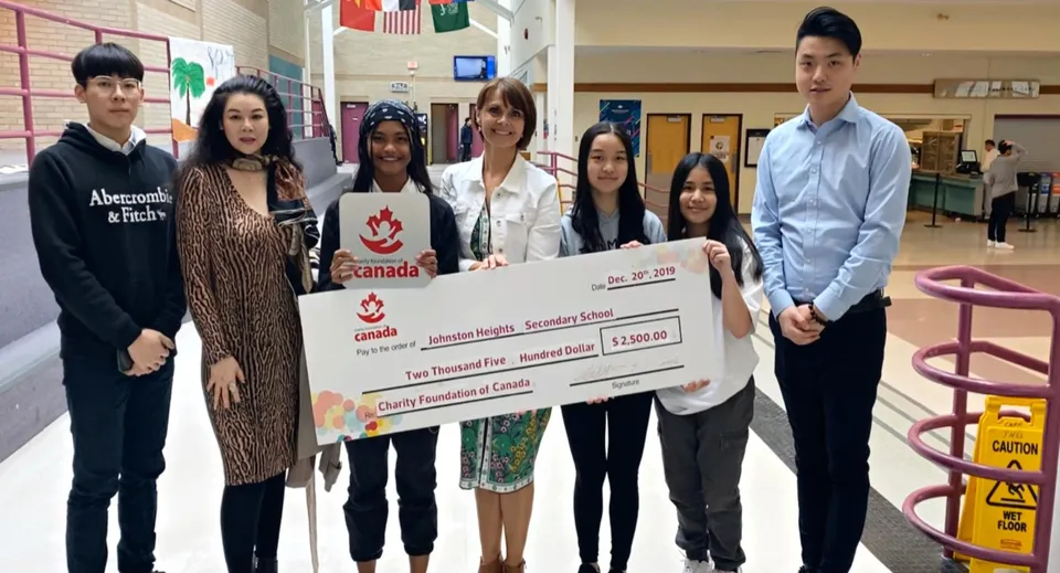 Studenti della Johnston Heights Secondary School presentano un grande assegno durante la consegna di una donazione.